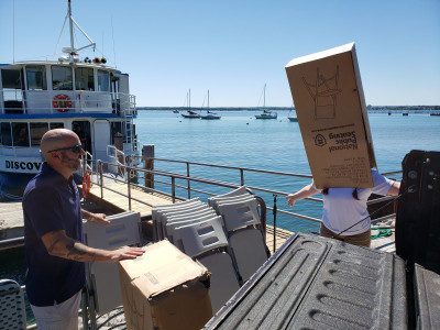 Crewmember Brea showing crewmember Marc how to box the folding chairs after a private charter